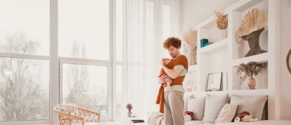 A woman sits outside at a wooden table in the evening sun and is researching early retirement on her laptop.